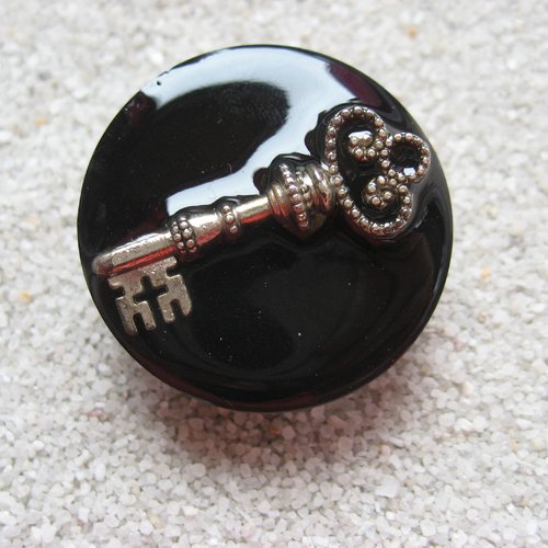 Grande bague ajustable unisexe clé argentée sur fond noir en résine diamètre 35mm