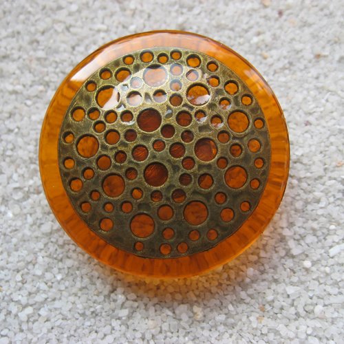 Très grande bague ajustable unisexe estampe bronze trouée sur fond orange en résine diamètre 40mm