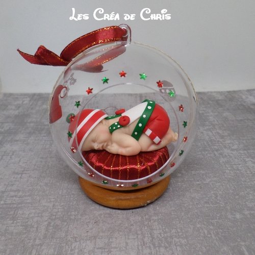 Bébé fimo thème de noël dans sa boule à suspendre au sapin.