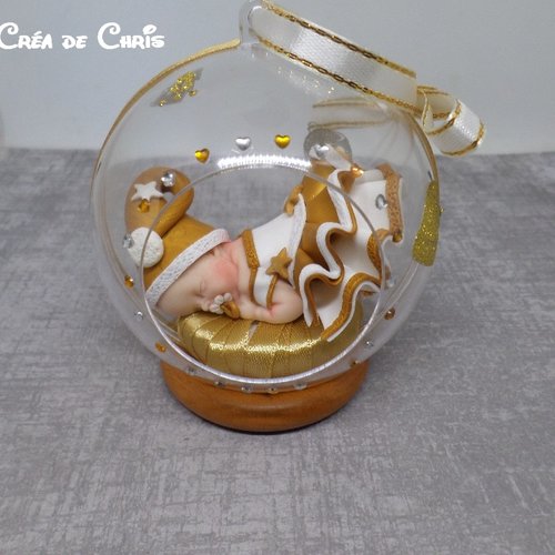 Bébé fimo thème de noël dans sa boule à suspendre au sapin.