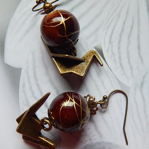 Boucles d' oreille pendantes, breloques grues et perles marron.
