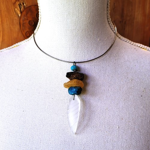 Un collier torque minimaliste avec un pendentif grigri porte-bonheur: "des poussières natures de mer"