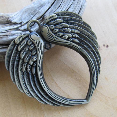 Pendentif  arrondi de 73 x 69 mm, motif "paire d'aile" en métal de couleur bronze. 
