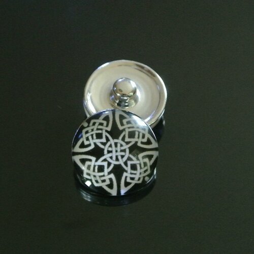 Un bouton pression snap en verre diamètre 18 mm, motifs entrelacs celtiques blancs sur fond noir, pression : 5,5