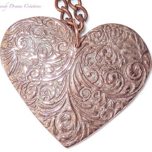 Collier coeur aux motifs  raffinés, couleur cuivre clair , reliefs lumineux, création artisanale  en pâte de cuivre