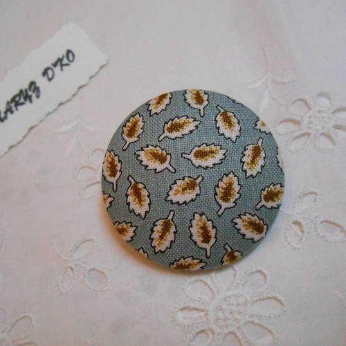 Bouton tissu 40mm recouvert d'un coton feuilles fond bleu 