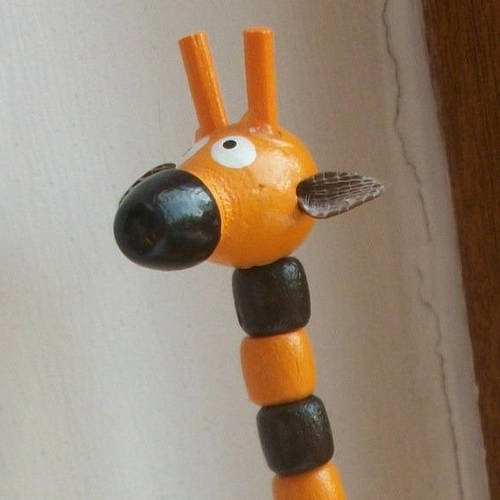 Un petit jouet girafe en bois animé à faire tomber en appuyant sous le socle orange noir