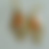 Boucles d'oreilles graphiques sequin navette émaillé orange clair derrière un support doré forme losange