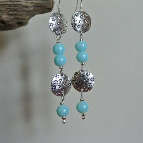 Boucles d'oreilles constituées de perles en verre bleu ciel satiné et de petits connecteurs boucliers  gravés de petites fleurs en métal