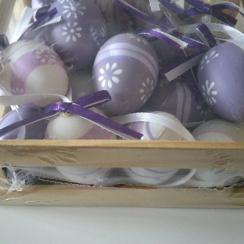 Petite caisse en bois contenant des oeufs décorés dans les tons violet, mauve, parme