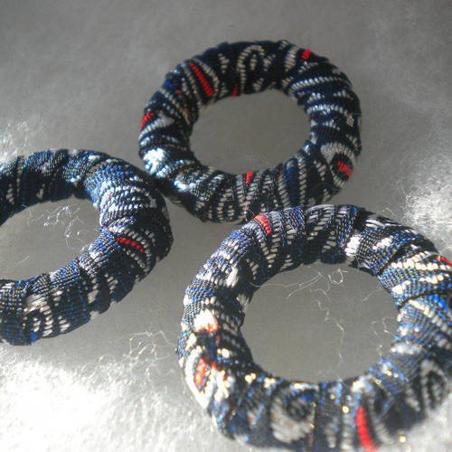 Trois anneaux recouverts de tissus en bleu argenté et rouge 