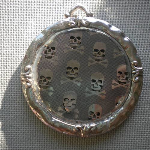 Grand pendentif rond en métal ajouré têtes de mort 