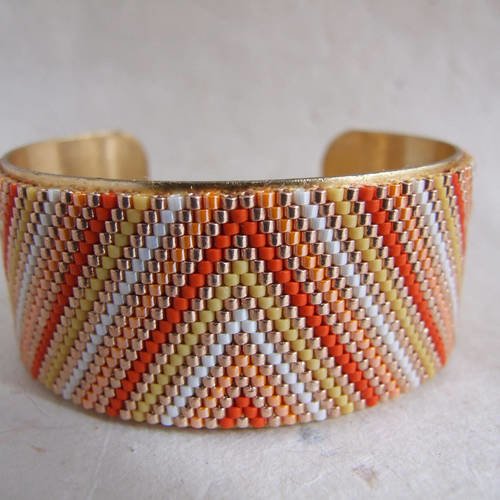 Bracelet manchette tissé en perles miyuki jaune, orange, rouge, blanc et doré selon un motif de triangles et de lignes