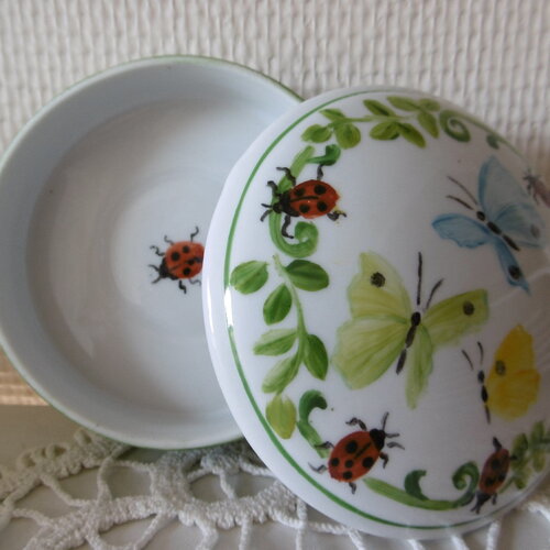 Boîte ronde en porcelaine peinte main : 3 papillons en tourés d'une guirlande avec 4 coccinelles
