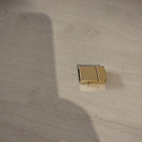Un fermoir magnétique rectangulaire en acier de couleur dorée