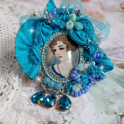 Pendentif mademoiselle d’un style rétro avec un cabochon d’une femme souriante, cristaux, perles, soie bleu et argent 925/1000