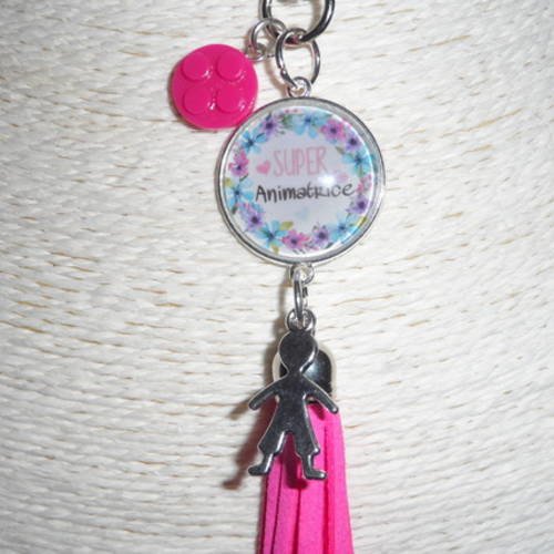 Porte clés / bijou de sacs cabochon " super animatrice  " avec breloques et pompon rose. 