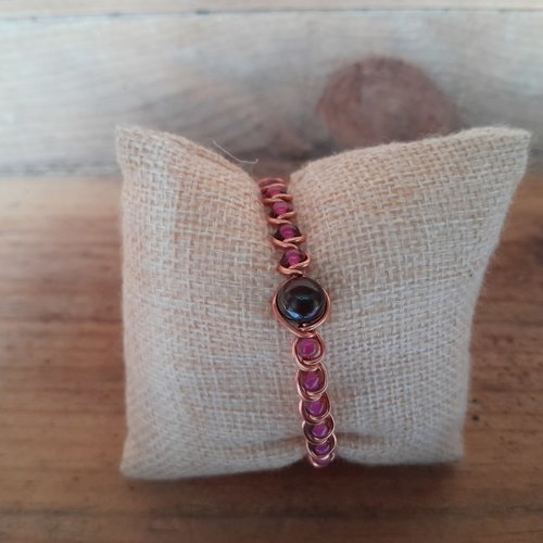 Bracelet en cuivre "œil de taureau" avec des perles de rocaille rose foncé.