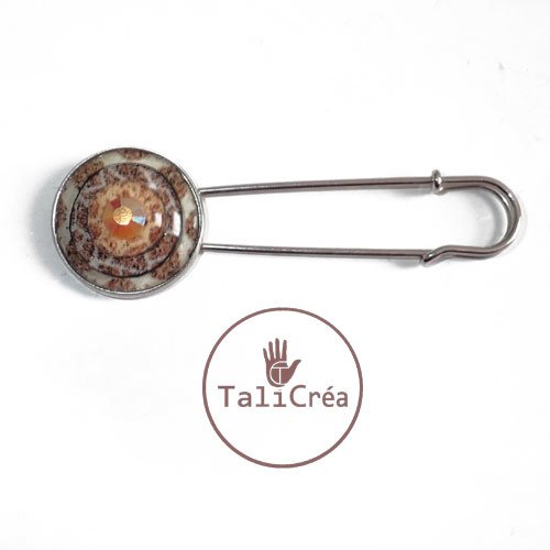 Une épingle à nourrice argentée en sables bordeaux blanc jaune