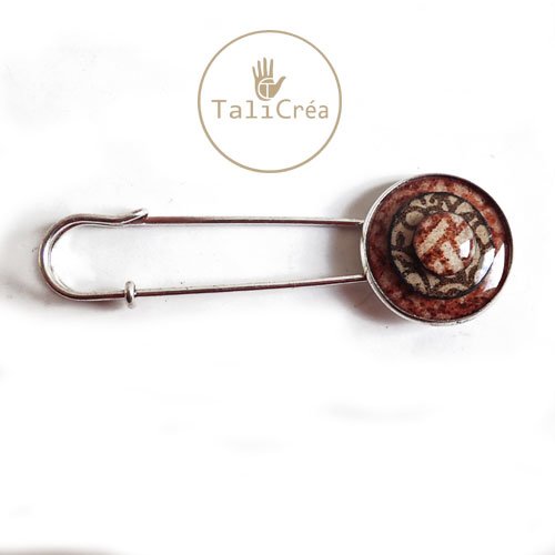 Une épingle à nourrice argentée celte en sables rouges, jaunes, marron