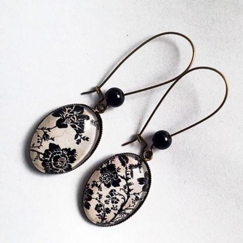Boucles d'oreille pendantes, en bronze, cabochons ovales, fleurs noires sur fond beige, perles noires. 