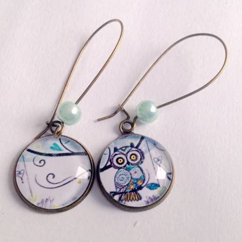 Boucles d'oreille pendantes asymétriques hibou tons bleus et blancs, cabochons en verre, en bronze, perles. 