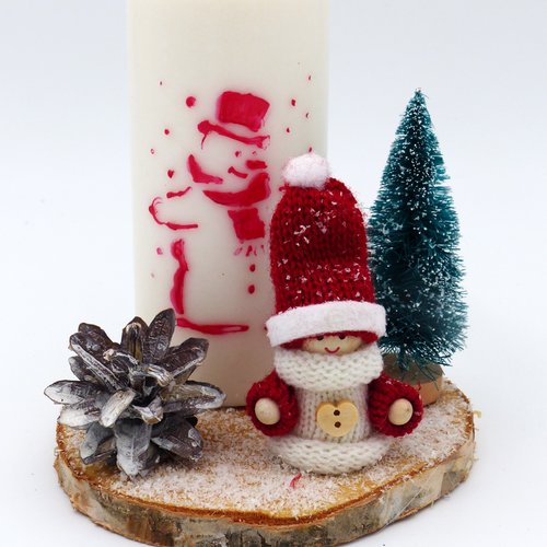 Centre de table composé d'une bougie de 12 cm sur laquelle est peint un bonhomme de neige et d'un décor de noël