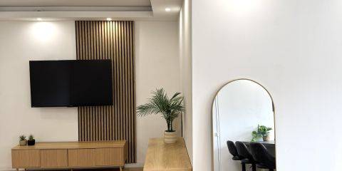 Espace séjour avec un grand canapé sur la gauche et une SmartTV 55"